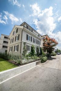 ein großes weißes Gebäude an der Straßenseite in der Unterkunft Tilia Apartments in Uster