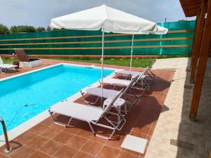 a group of chairs and an umbrella next to a swimming pool at Maria Lemoni swimming pool apartment in Nea Skioni