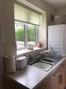 a white kitchen with a sink and a window at No 96 Chapel Lane - Self Contained Cottage In The Heart Of Butleigh in Butleigh