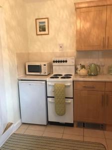 een keuken met een wit fornuis en een magnetron bij No 96 Chapel Lane - Self Contained Cottage In The Heart Of Butleigh in Butleigh