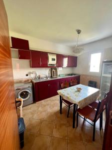 uma cozinha com armários vermelhos e uma mesa com cadeiras em Relax Island em Oued Laou
