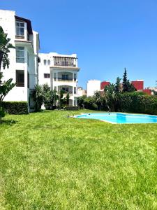 a swimming pool in the grass in front of a building at Relax Island in Oued Laou