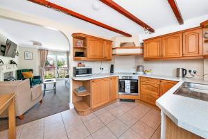 a kitchen with wooden cabinets and a living room at Finest Retreats - Bilsdale Hall Cottage in Thirsk