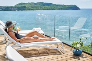 une femme assise sur une chaise sur une terrasse avec un verre dans l'établissement Hotel Basalto, à Punta Mita