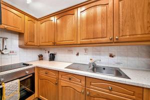 a kitchen with wooden cabinets and a sink at Finest Retreats - Hambleton Hall Apt in Thirsk