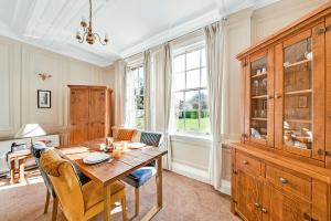 a dining room with a table and a large wooden cabinet at Finest Retreats - Mowbray Hall Apt in Thirsk