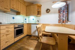 uma cozinha com armários de madeira e uma mesa e cadeira de madeira em Lindenhof Apt 5 em Vandoies