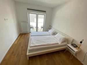 a white bedroom with a bed and a table at Loft Appartement Seven in Friedrichshafen