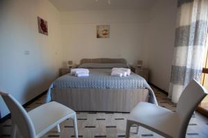 a bedroom with a bed with two white chairs at Al Centro in Gangi