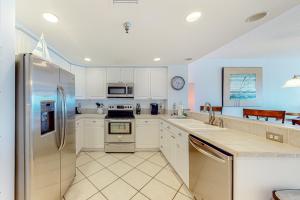 a kitchen with white cabinets and a stainless steel refrigerator at Emerald Isle 1105 in Pensacola Beach