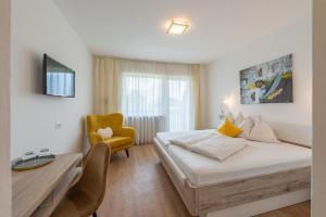 a bedroom with a bed and a desk and a chair at Hotel Garni Vinea Montis in Termeno