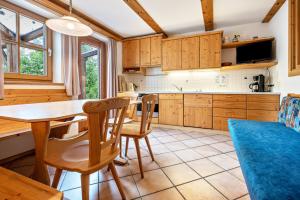 una cocina con armarios de madera, mesa y sillas en Lindenhof Apt 8, en Vandoies