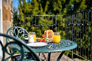 une table avec une assiette de nourriture et deux verres de jus d'orange dans l'établissement Finest Retreats - Roulston Hall Apt, à Thirsk