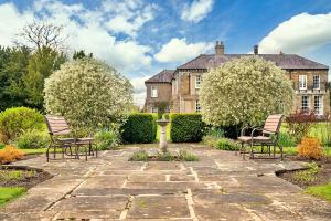 a garden with chairs and a fountain in front of a house at Finest Retreats - Roulston Hall Apt in Thirsk