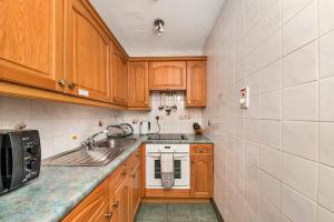 eine kleine Küche mit Holzschränken und einem Waschbecken in der Unterkunft Finest Retreats - Roulston Hall Apt in Thirsk
