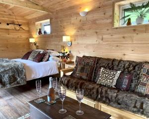 a room with two beds and a couch and wine glasses at TVF Stable Suites in Nether Stowey