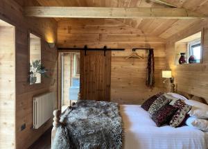 1 dormitorio con 1 cama en una habitación con paredes de madera en TVF Stable Suites en Nether Stowey