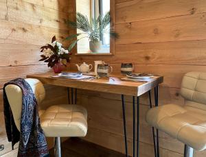 Zimmer mit einer Holzwand mit einem Tisch und 2 Stühlen in der Unterkunft TVF Stable Suites in Nether Stowey