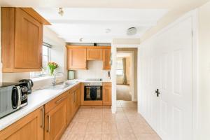 a kitchen with wooden cabinets and a white door at Finest Retreats - Ryedale Hall Cottage in Thirsk