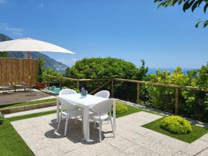 eine Terrasse mit einem Tisch, Stühlen und einem Sonnenschirm in der Unterkunft Cottage L'Americano in Positano