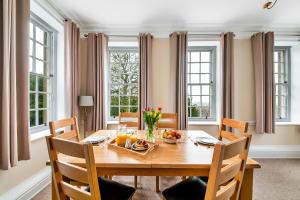 a dining room with a wooden table and chairs and windows at Finest Retreats - York Hall Apt in Thirsk