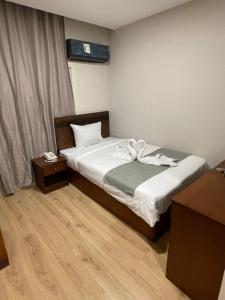 um quarto de hotel com uma cama com lençóis brancos em Miramar Evergreen Hotel no Cairo