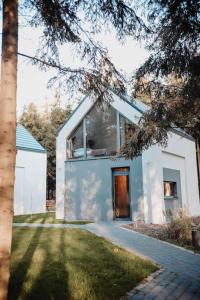 Una casa blanca con un árbol delante. en Apartamenty Leśne Historie 1, en Gołuchów