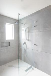 La salle de bains est pourvue d'une douche avec une porte en verre. dans l'établissement Mandakini villa, à New Delhi
