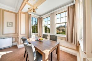 a dining room with a wooden table and chairs and windows at Finest Retreats - Sutton Hall Apt in Thirsk