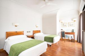 een slaapkamer met twee bedden, een bureau en een stoel bij Hotel Hernán Cortés in Gijón +37 foto's