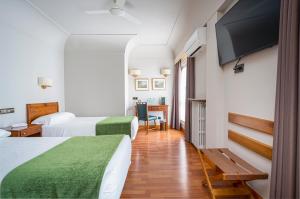 een hotelkamer met twee bedden en een flatscreen-tv bij Hotel Hernán Cortés in Gijón