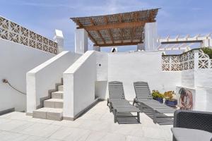een patio met stoelen en trappen in een wit gebouw bij One Bedroom Penthouse in Nerja