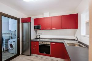 a kitchen with red cabinets and a stainless steel refrigerator at Casa Albatros - luxuriöses Penthouse-Apartment in Caleta De Fuste