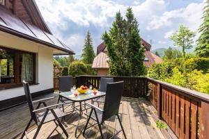 een terras met een tafel en stoelen op een dek bij Willa Marta Zakopane in Zakopane