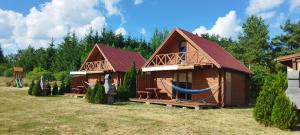 duas casas de madeira com rede num quintal em Domki Letniskowe Kosewo em Kosewo