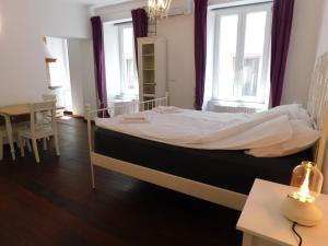 a bedroom with a bed with white sheets and windows at Apartment Keymaster's Hideaway in Ljubljana