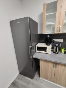 a stainless steel refrigerator in a kitchen with a microwave at UBYTOVŇA BYTČA in Bytca