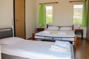 2 łóżka w pokoju z zielonymi zasłonami w obiekcie Ateni House w mieście Agios Petros
