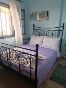 a bedroom with a black bed with purple sheets and a window at Karpetis a green paradise in Psakoudia