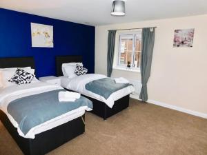 a bedroom with two beds and a blue wall at AMILA House Manchester, Modern, Spacious, Sleeps 7 With Parking in Manchester