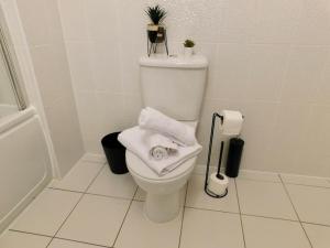 a white bathroom with a toilet with towels on it at AMILA House Manchester, Modern, Spacious, Sleeps 7 With Parking in Manchester