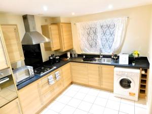 a kitchen with a sink and a washing machine at AMILA House Manchester, Modern, Spacious, Sleeps 7 With Parking in Manchester