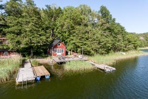 uma casa na margem de um lago com uma doca em Fishermans cabin em Myttinge