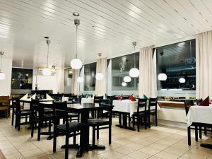 Un comedor con mesas y sillas y ventanas. en Hotel Stadthof Glarus, en Glaris