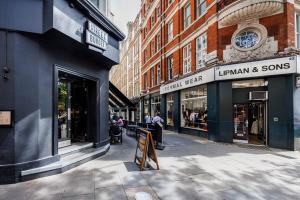 a city street with shops and buildings with a clock at Charing Cross Road One Bedroom in London