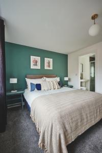 um quarto com uma cama grande e paredes azuis em Coventry Home for 6+2, 150Mbp Wi-Fi + Parking em Canley