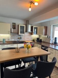 a kitchen with a wooden table with chairs and a vase of flowers at Fewo an der Stever in Lüdinghausen