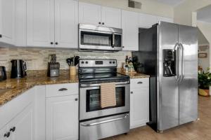 a kitchen with white cabinets and a stainless steel refrigerator at Private oasis, Pool, Downtown PNS & Beach 3BR-2,5BT in Pensacola