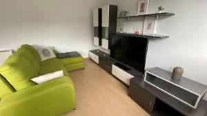 sala de estar con sofá verde y TV de pantalla plana en A CUARTA RONDA, en Melide