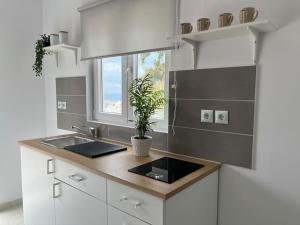 a white kitchen with a sink and a window at Πανοραμικό Ηλιοβασίλεμα in Ios Chora